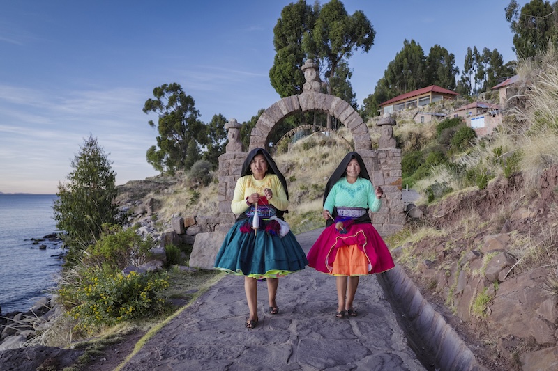 Young girls spinning a wool by hand on Taquile Island, Lake Titicaca, Peru