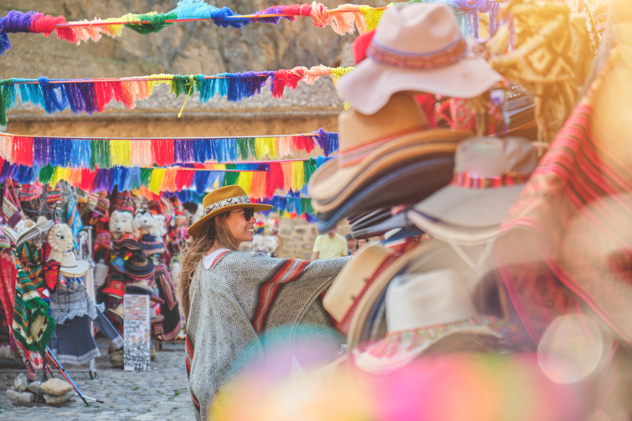 Traveler girl in hat with backpack selling in market of Ollantaytambo Ruins in Sacred Valley of Peru. travel Concept