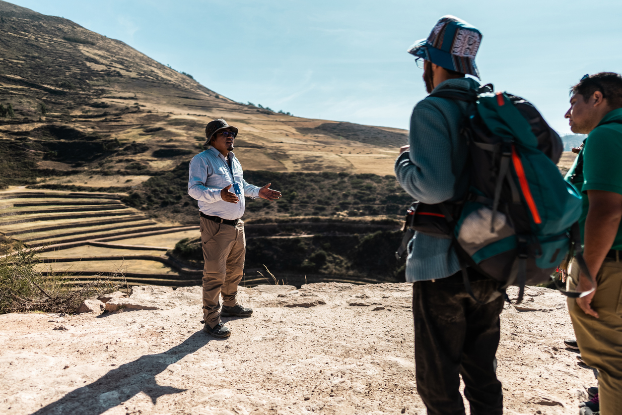 Tour guide talking with tourist on mountain, in Moray, Peru