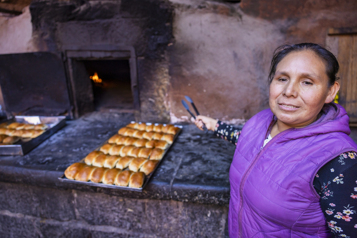 Peruvian woman baking empanadas in old colonial clay oven, Pisac, Urubamba Valley