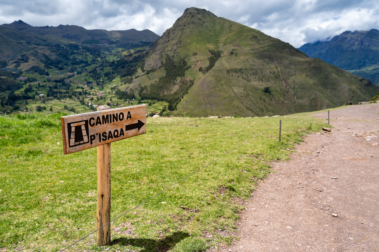 Wooden sign indicating the hiking trail from Pisac Archaeological Park to Pisac town.