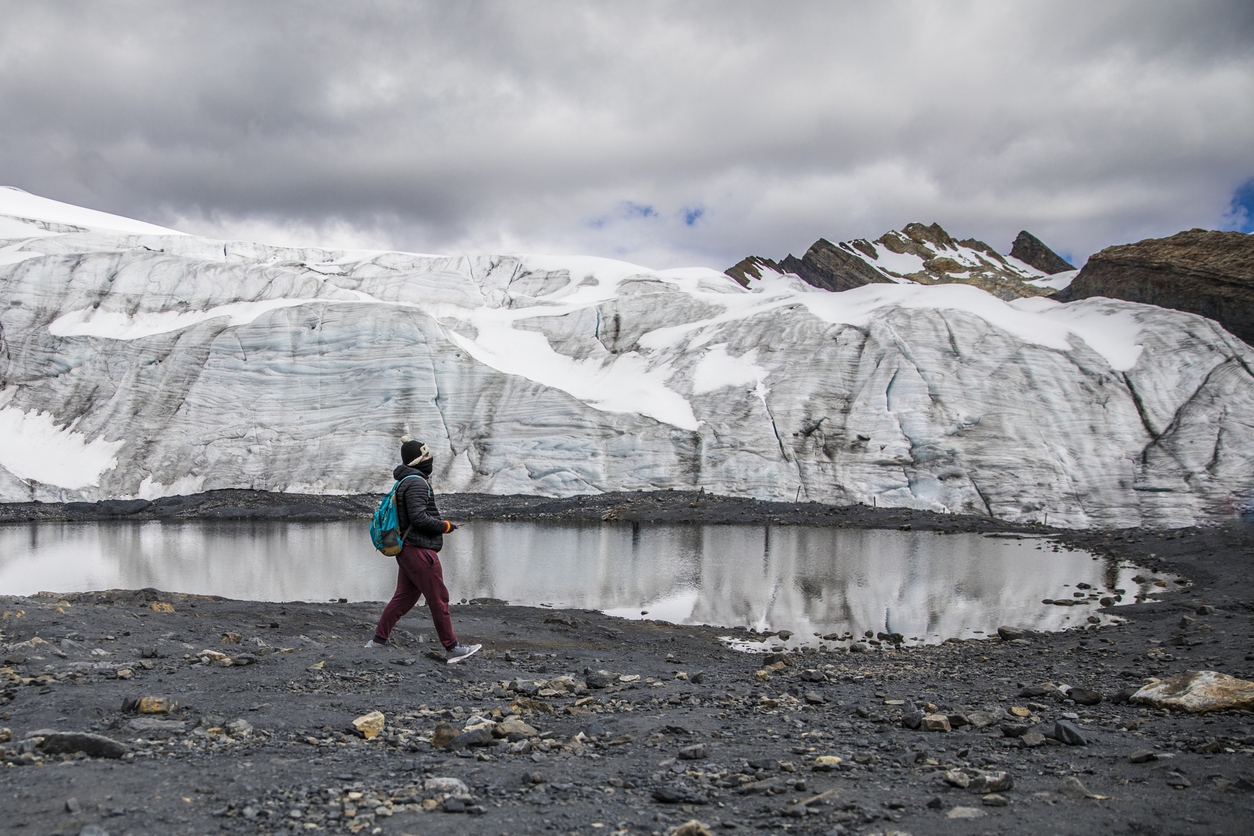man walking in a glacier, little lake and cloudy