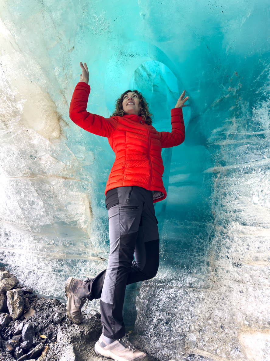 Female traveler in red jacket inside ice cave at Quelccaya glacier Peru